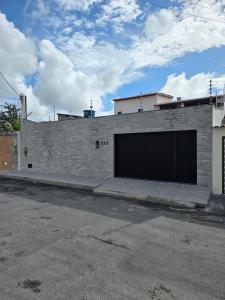a brick building with two garage doors on a street at Inocoop house in Camaçari