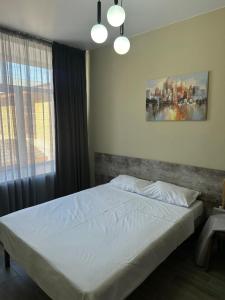 a bedroom with a white bed with a window at Assorti in Semey