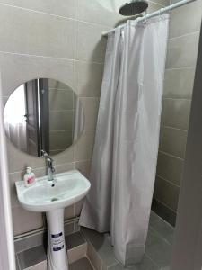 a bathroom with a sink and a shower curtain at Assorti in Semey