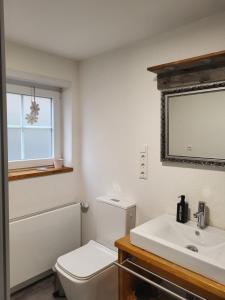 a bathroom with a white toilet and a sink at Ferienwohnung Kraichgaublick in Angelbachtal +27 photos