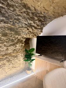 a tv sitting on a stand next to a stone wall at Casa Cueva Transmina 10 in Setenil