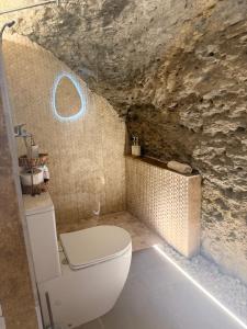 a bathroom with a toilet and a stone wall at Casa Cueva Transmina 10 in Setenil +15 photos