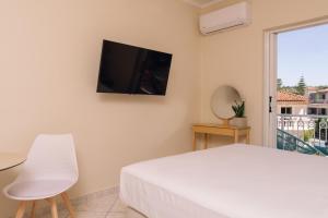 a bedroom with a bed and a television on the wall at Maroudas Apartments in Planos
