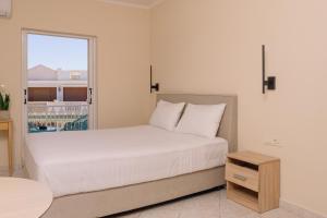 a bedroom with a large white bed with a window at Maroudas Apartments in Planos