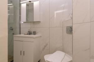 a white bathroom with a toilet and a shower at Maroudas Apartments in Planos +3 photos