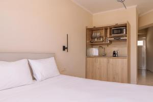 a bedroom with a white bed and a microwave at Maroudas Apartments in Planos
