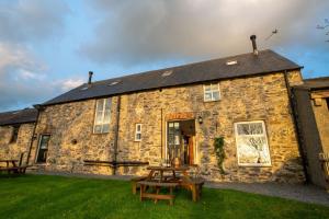 a stone building with a picnic table in front of it at Bryn Lon in Caeʼr-geiliog