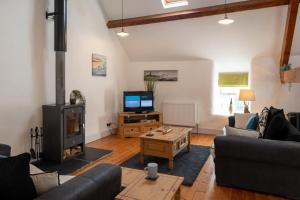 a living room with a couch and a tv at Bryn Lon in Caeʼr-geiliog