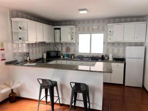 a kitchen with white cabinets and two bar stools at Meu Quintal 1, Calheta-Madeira in Calheta