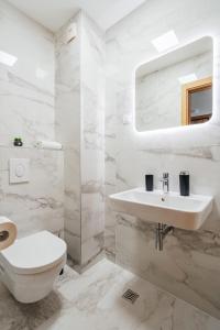 a white bathroom with a sink and a toilet at APART 28 - Premium Suites in Podgorica +58 photos