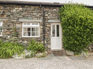 a stone house with a white door and a window at Cottage 1 in Keswick