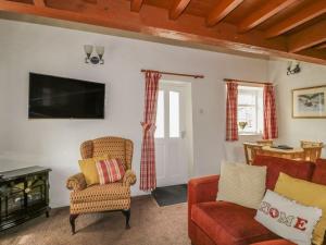 a living room with two chairs and a tv at Cottage 1 in Keswick +6 photos