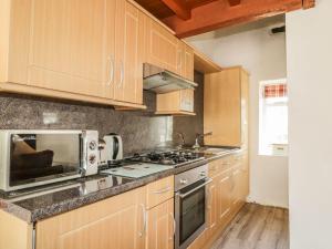 a kitchen with wooden cabinets and a microwave at Cottage 1 in Keswick