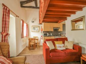 a living room with a red couch and a kitchen at Cottage 1 in Keswick
