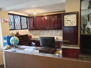 an office with a clock and a desk with a laptop at Hotel Gavilu in Ambato +28 photos