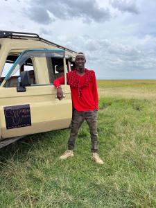 a man standing in the grass next to a van at Escape Haven Mara in Masai Mara +5 photos