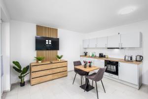 a kitchen with white cabinets and a wooden table and chairs at BrockHeus Riverside Aparthotel Magdeburg in Magdeburg +30 photos