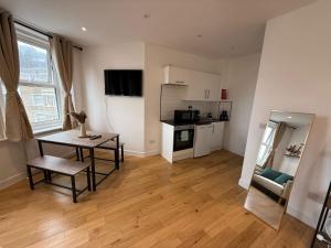 a living room with a table and a kitchen at The Kove Oceanview in Bournemouth