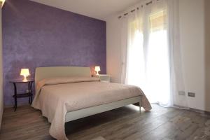 a bedroom with a bed with a purple wall at Appartamento Dea in Marina di Campo