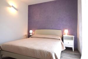 a bedroom with a bed and a purple wall at Appartamento Dea in Marina di Campo +6 photos