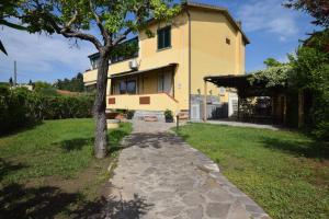 a house with a tree next to a walkway at Appartamento Dea in Marina di Campo