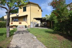 a large yellow house with a tree and a walkway at Appartamento Dea in Marina di Campo