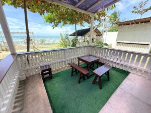 a porch with two benches and a table and chairs at DJL Beach House - Bantayan Island in Patao
