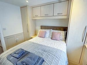 a small bedroom with a bed with pink and blue pillows at Little Nauvoo in Bath