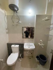 a man taking a picture of a bathroom with a toilet and sink at Cozy Inn Hotel in Noida