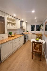 a kitchen with white cabinets and a table and chairs at Spacious Double Room in Shared Flat in Sutton