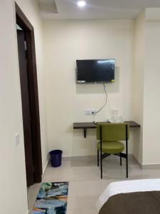 a room with a desk and a television on the wall at Cozy Inn Hotel in Noida