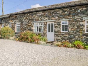 a stone cottage with a white door and windows at Cottage 2 in Keswick