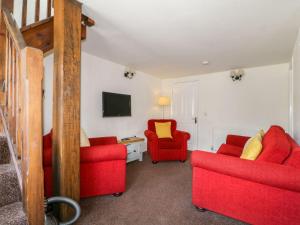 a living room with red chairs and a tv at Cottage 2 in Keswick