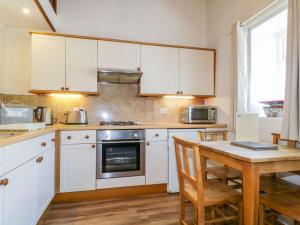 a kitchen with white cabinets and a wooden table at Cottage 2 in Keswick