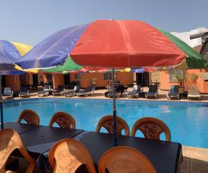 a table with an umbrella next to a swimming pool at Avalon Garden Lodge in Banjul