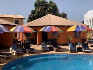 a pool with chairs and umbrellas next to a building at Avalon Garden Lodge in Banjul