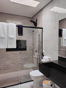 a bathroom with a toilet and a glass shower at Studios Leme 11 - conforto para casal - com varanda in Espirito Santo Do Pinhal +22 photos