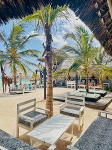 a beach with benches and palm trees on the beach at Luwa Beach&Suits in Watamu