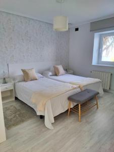 a bedroom with two beds and a chair and a window at Tu Casina del Norte in Luanco