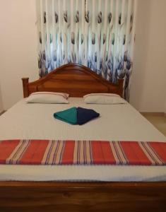 a bed with a wooden headboard and two pillows at Thisu villa in Weligama