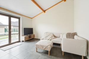 a living room with a white couch and a tv at Duinhuis 20 P in Oostduinkerke
