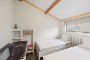 two beds in a small room with a window at Duinhuis 20 P in Oostduinkerke