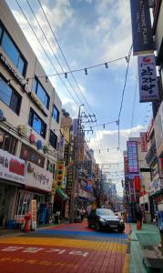 a black car driving down a city street with buildings at La Petite Maison d'Hôtes in Seoul