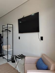 a living room with a couch and a flat screen tv on a wall at Studios Leme 11 - conforto para casal - com varanda in Espirito Santo Do Pinhal
