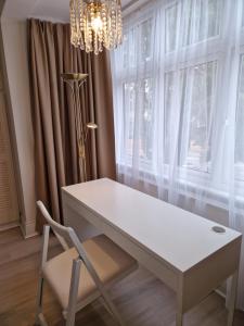 a white desk in front of a window with a chandelier at Osterley Room in Isleworth +13 photos