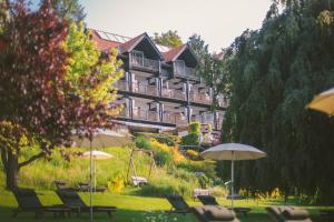 a hotel with chairs and umbrellas in a park at Kleines Hotel Kärnten in Egg am Faaker See