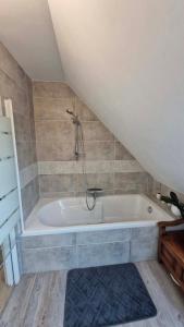 a bath tub with a shower in a attic at Chambre confortable chez Isabelle in Cléden-Cap-Sizun