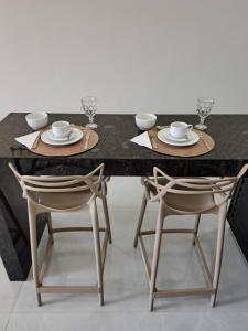 a dining table and two chairs with plates and cups at Studios Leme 11 - conforto para casal - com varanda in Espirito Santo Do Pinhal