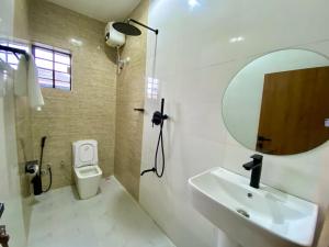 a bathroom with a sink and a mirror and a toilet at Ghomes in Lagos