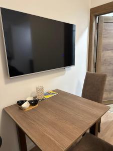 a wooden table with a large television on a wall at Happy moments Studio Kraljevo in Kraljevo
